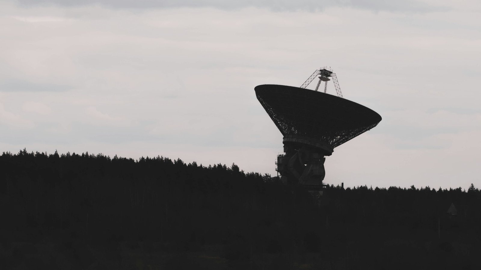 A radio telescope silhouetted against the sky.