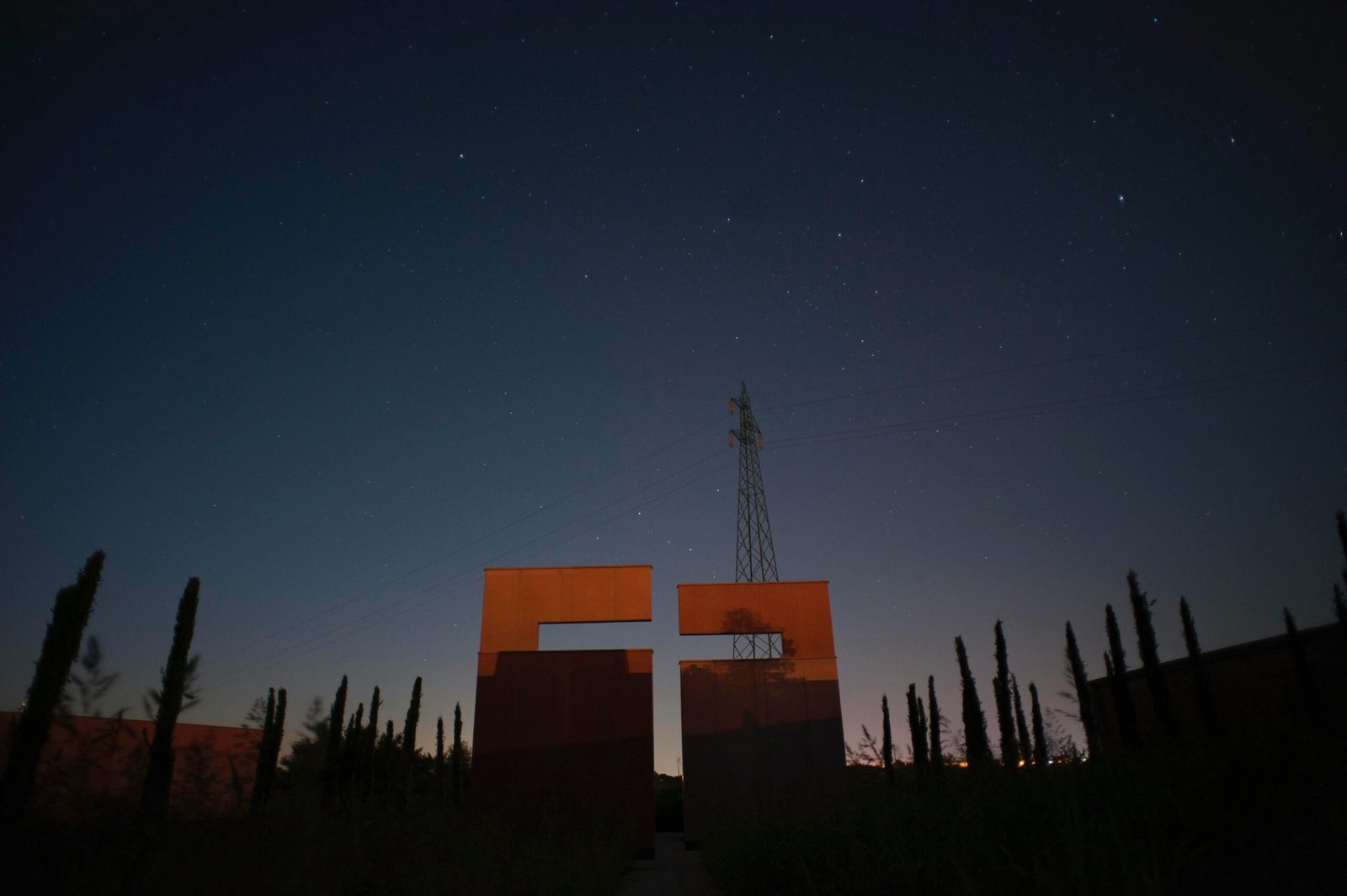 CROSS OF AIR 
ph. Davide Menis
EXTENSION OF CEMETERY VALLE ISOLA 
The master plan that we are proposing for the existing cemetery in Comacchio aims to convey an idea of “completeness”, although only one quadrant will be built presently. At the center of the wood and positioned at the terminus of a long axis is a large cross, a cross of air created by the negative space carved from two adjacent walls. Here, the widow dressed in black can bring her folding chair, sit quietly with her beloved in a serene, small court to talk about the present and the past, to visit and cry in peace.